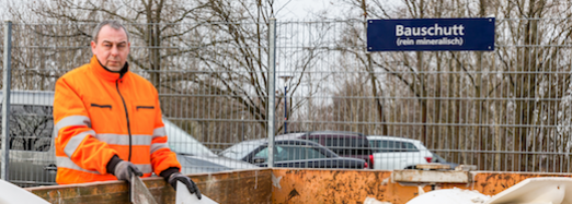 SAS-Mitarbeiter Andreas Peters zeigt, was alles in den Container für den mineralischen Bauschutt gebracht werden darf, Foto: maxpress/srk